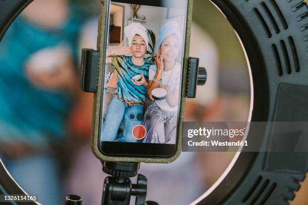 female influencers applying face cream while making tutorial at home - influencer stock-fotos und bilder