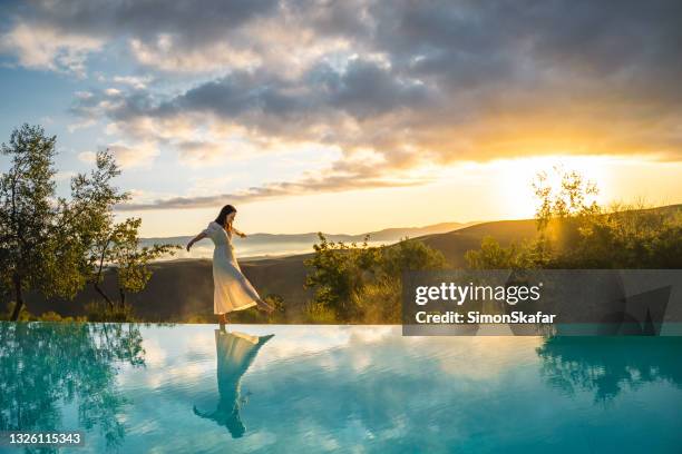 mujer caminando en el borde de la piscina infinita - lujo fotografías e imágenes de stock