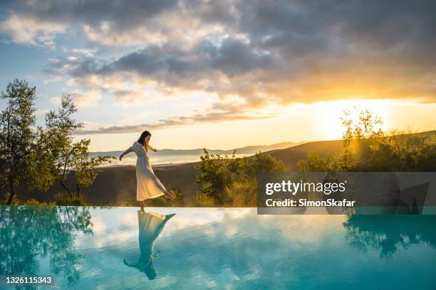 femme marchant sur le bord de la piscine à débordement - premium photos et images de collection