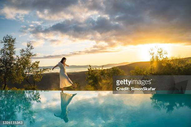 woman walking on the edge of infinity pool - women by pool imagens e fotografias de stock
