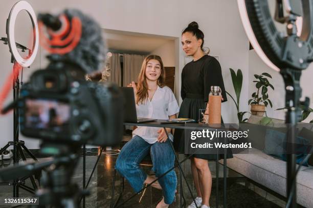 female professionals working on laptop while vlogging at office - filmteam stockfoto's en -beelden