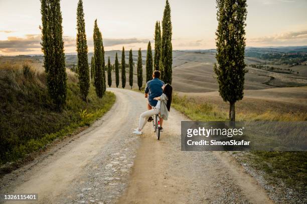 pareja montando en la bicicleta - tuscany fotografías e imágenes de stock