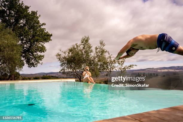 young man jumping into the swimming pool - tuscan villa stock pictures, royalty-free photos & images