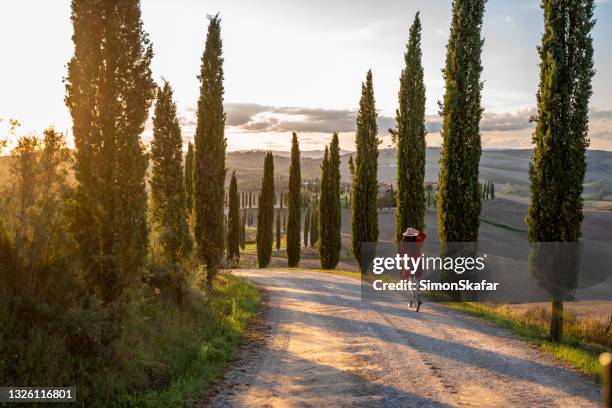 woman riding a bicycle during sunset in tuscany - italie stockfoto's en -beelden