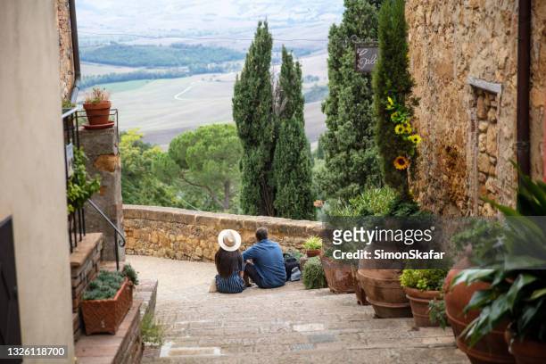 vista posteriore di una coppia seduta sulle scale, pienza, italia - village foto e immagini stock