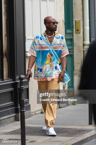 Guest wears black sunglasses, a silver chain necklace, a white with orange / blue and a photo of a woman in a bikini print pattern and 'Monte Carlo'...