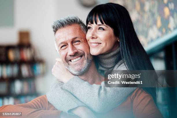 smiling woman embracing man from behind at cafe - straight hair ストックフォトと画像