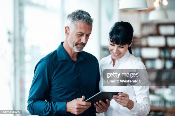 smiling professional team using digital tablet in coffee shop - two executive man coffee shop stock-fotos und bilder