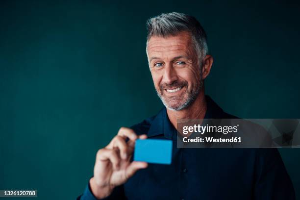 smiling businessman holding card against green background - portrait holding card foto e immagini stock