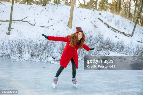 cheerful woman with arms outstretched enjoying ice-skating on frozen lake - ice rink stock pictures, royalty-free photos & images