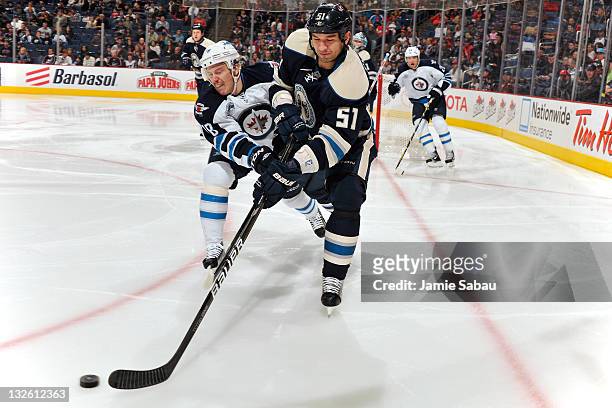 Fedor Tyutin of the Columbus Blue Jackets knocks the puck away from Bryan Little of the Winnipeg Jets during the second period on November 12, 2011...