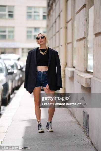 Emy Venturini wears black Ray Ban sunglasses, a gold large chain necklace from Maison Margiela, a black ribbed long sleeves crop-top fom Elisabetta...