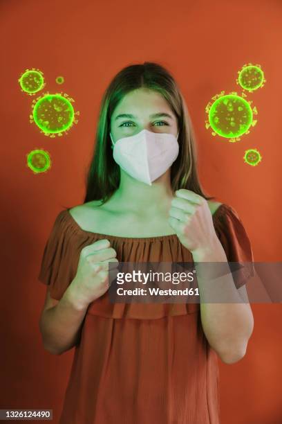 stockillustraties, clipart, cartoons en iconen met girl wearing protective face mask standing in fighting stance amidst coronavirus over red background - pandemia