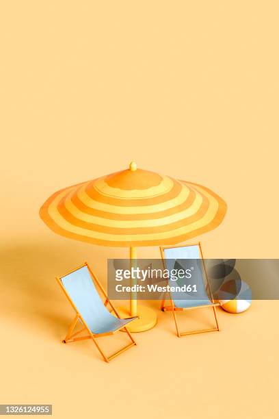 studio shot of beach umbrella, two empty deck chairs and beach ball - beach deck chairs stock-fotos und bilder