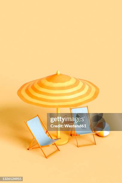 studio shot of beach umbrella, two empty deck chairs and beach ball - toldo fotografías e imágenes de stock