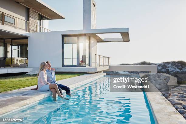 relaxed couple sitting together at pool in backyard - backyard pool fotografías e imágenes de stock