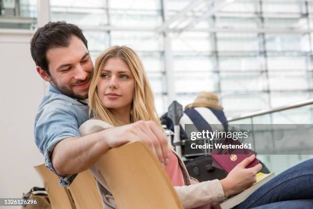 young couple with passport waiting in airport departure area - german passports stock-fotos und bilder