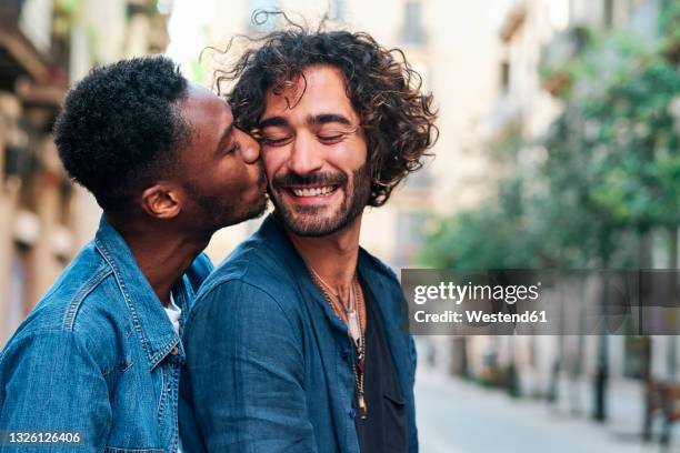 affectionate gay man kissing happy boyfriend - interracial kissing stock pictures, royalty-free photos & images