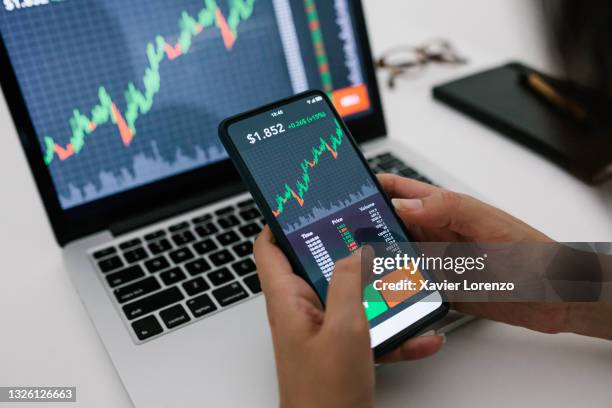 woman using stock trading app on smart phone at home - portfolio stock pictures, royalty-free photos & images