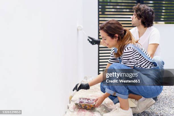 mid adult couple paining new home - messy boyfriend stock pictures, royalty-free photos & images