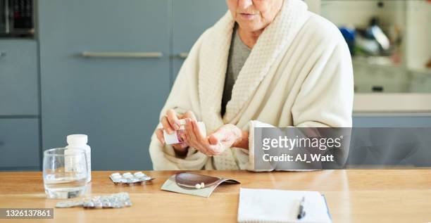 donna anziana che prende la sua medicina quotidiana nella sua cucina al mattino - week one foto e immagini stock