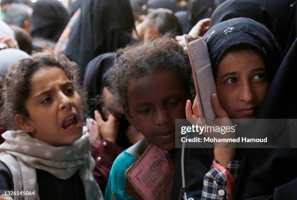 Yemeni girls, from families who were affected by the war and blockade, flock to receive free lunch meals, provided by a charitable kitchen at Mseek...