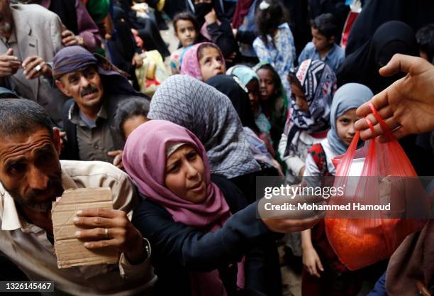 Yemeni people, from families who were affected by the war and blockade, flock to receive free lunch meals, provided by a charitable kitchen at Mseek...