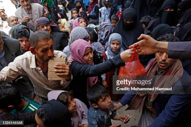 Yemeni people, from families who were affected by the war and blockade, flock to receive free lunch meals, provided by a charitable kitchen at Mseek...