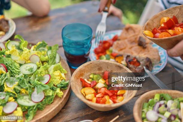 jeune famille mangeant de l’agneau, du bœuf et du kebab de légumes avec salade verte à l’extérieur - marine photos et images de collection