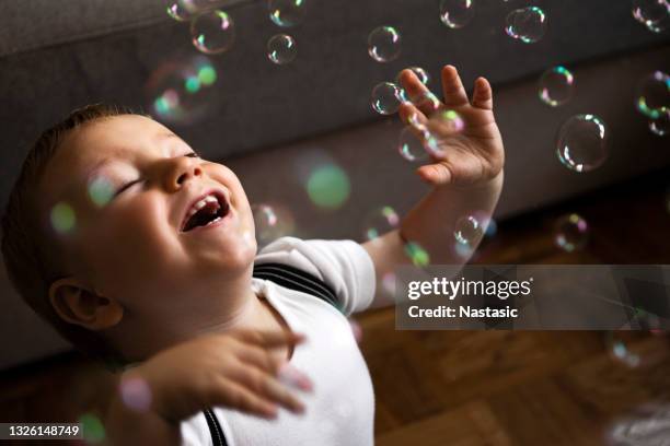 catching soap bubbles in living room - baby boy stock pictures, royalty-free photos & images