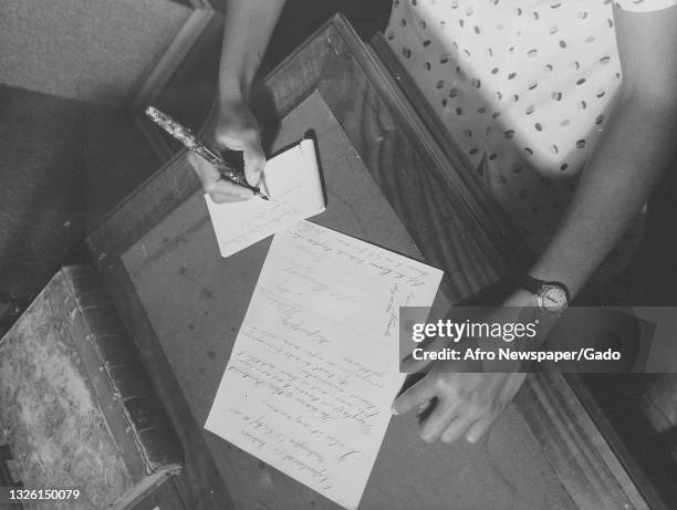 Black and white photograph of a worker taking notes about a document at the Frederick Douglass Memorial Home, the document is a letter from the...