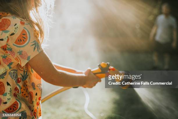 a child sprays a garden hose - tuinslang stockfoto's en -beelden