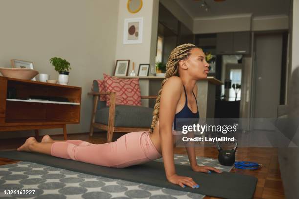 shot of a young woman doing a cobra stretch while exercising at home - cobra stretch stock pictures, royalty-free photos & images