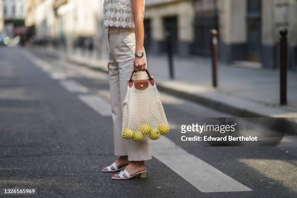 May Berthelot @may.berthelot wears a white tank top with mesh and embroidery from Longchamp, gray pants, a Longchamp fishnet bag containing apples,...