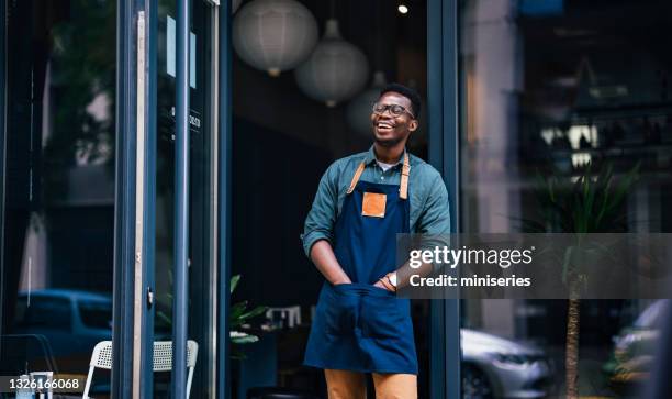 porträt eines selbstbewussten jungen mannes, der in der tür seines coffee shops steht - small business owner stock-fotos und bilder