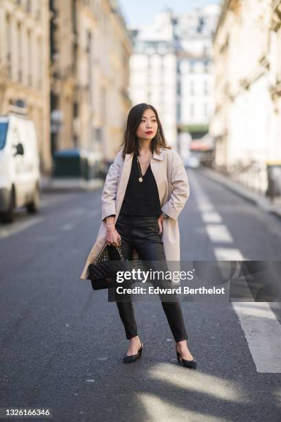 May Berthelot @may.berthelot wears a gray long Burberry trench coat, a black v-neck pullover top, black leather pants, a black leather quilted Chanel...