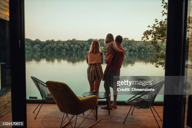 adorabile famiglia di tre persone sulla terrazza che guarda il fiume - lago foto e immagini stock