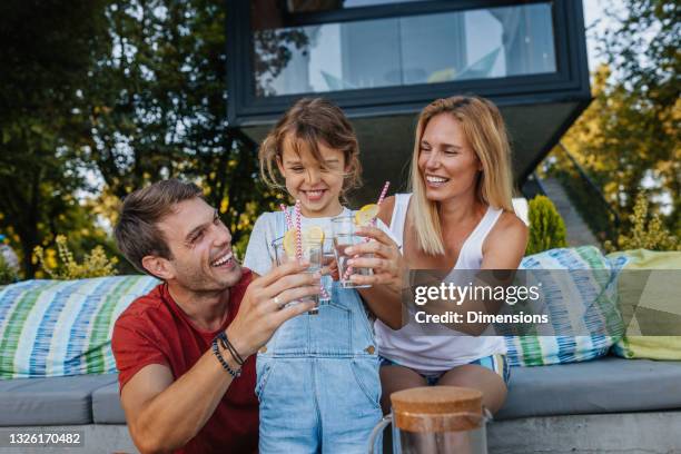 beautiful happy family toasting with refreshing water outdoors - limonade stockfoto's en -beelden