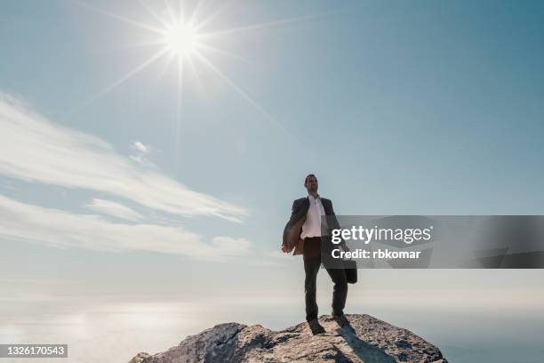 businessman freedom on the top of a high mountain against blue sky - business courage stock pictures, royalty-free photos & images