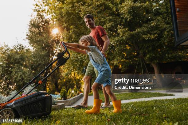 siempre ayuda a su padre en trabajos caseros - segadora fotografías e imágenes de stock