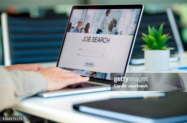 mature businessman looking at job search website on a laptop computer. - unemployment stock pictures, royalty-free photos & images