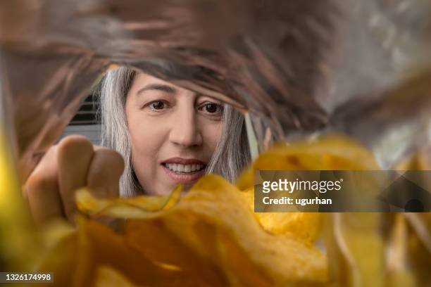 a woman eating chips from a package. - bag of chips stock pictures, royalty-free photos & images