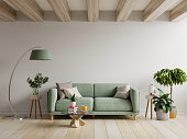 Green sofa in modern apartment interior with empty wall and wooden table.