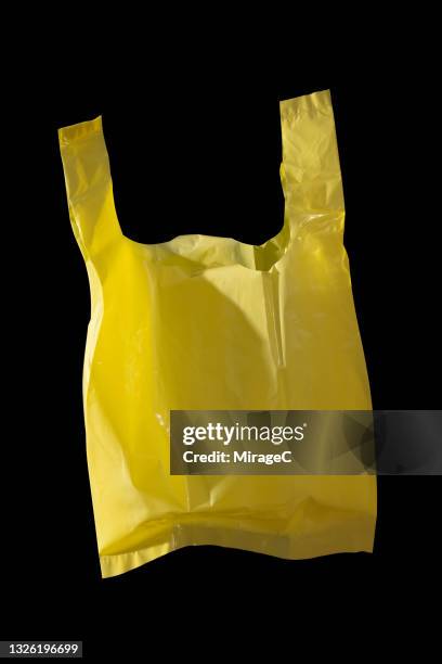 yellow colored plastic bag on black - sac en plastique photos et images de collection
