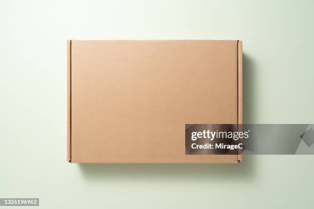 closed blank cardboard box on green - packing parcel stockfoto's en -beelden