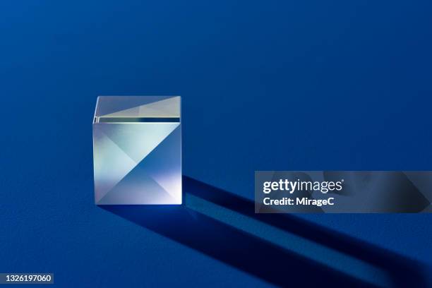 illuminated cube prism with shadow on blue - プリズム　レンズ ストックフォトと画像