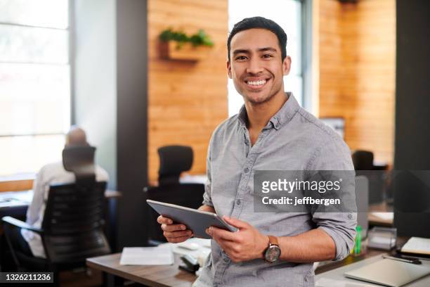 shot of a young businessman using a digital tablet in a modern office - confident young man at work stockfoto's en -beelden