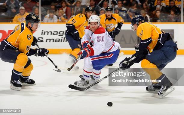 David Desharnais of the Montreal Canadiens passes the puck between Patric Horqnvist and Kevin Klein of the Nashville Predators at the Bridgestone...