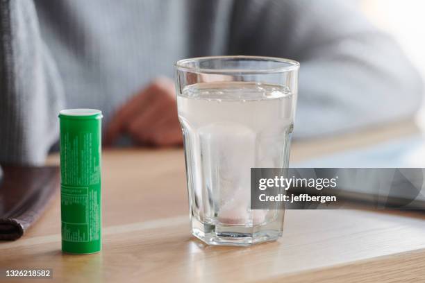 toma de una tableta efervescente que se disuelve en un vaso de agua - comprimido efervescente fotografías e imágenes de stock