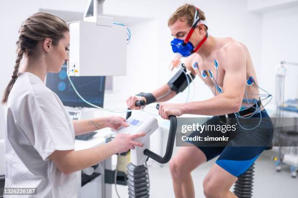 young male athlete taking a cardiopulmonary stress test in clinic - stress test stock pictures, royalty-free photos & images